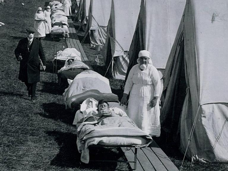 Eine Schwester und mit der Spanischen Grippe Infizierte in einem Notlazarett mit Zelten auf einer Grünfläche in Brookline, Massachusetts, USA, aufgenommen im Oktober 1918.