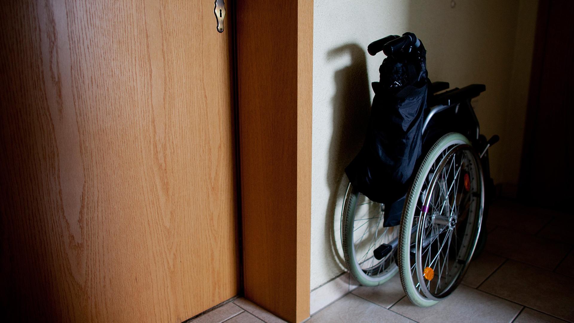 Ein Rollstuhl steht zusammengeklappt in einem Hausflur.