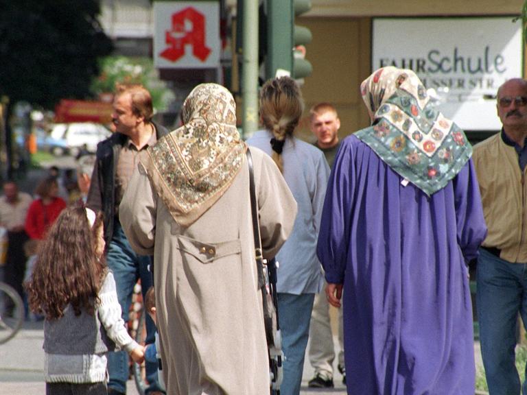 Zwei Frauen mit Kopftuch und andere Fußgänger in Berlin-Kreuzberg