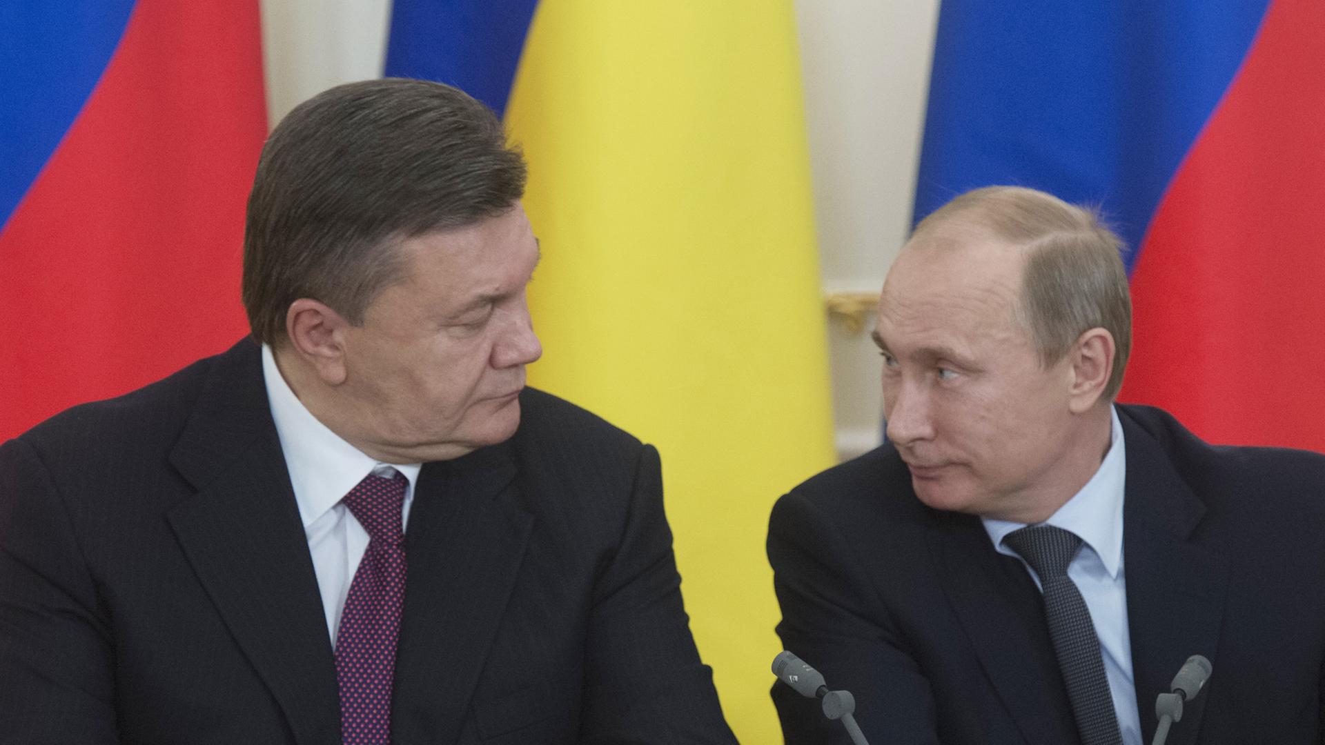 Der ukrainische Präsident Vktor Janukowitsch und sein russischer Amtskollege Wladimir Putin sitzen vor Flaggen ihrer jeweiligen Länder.