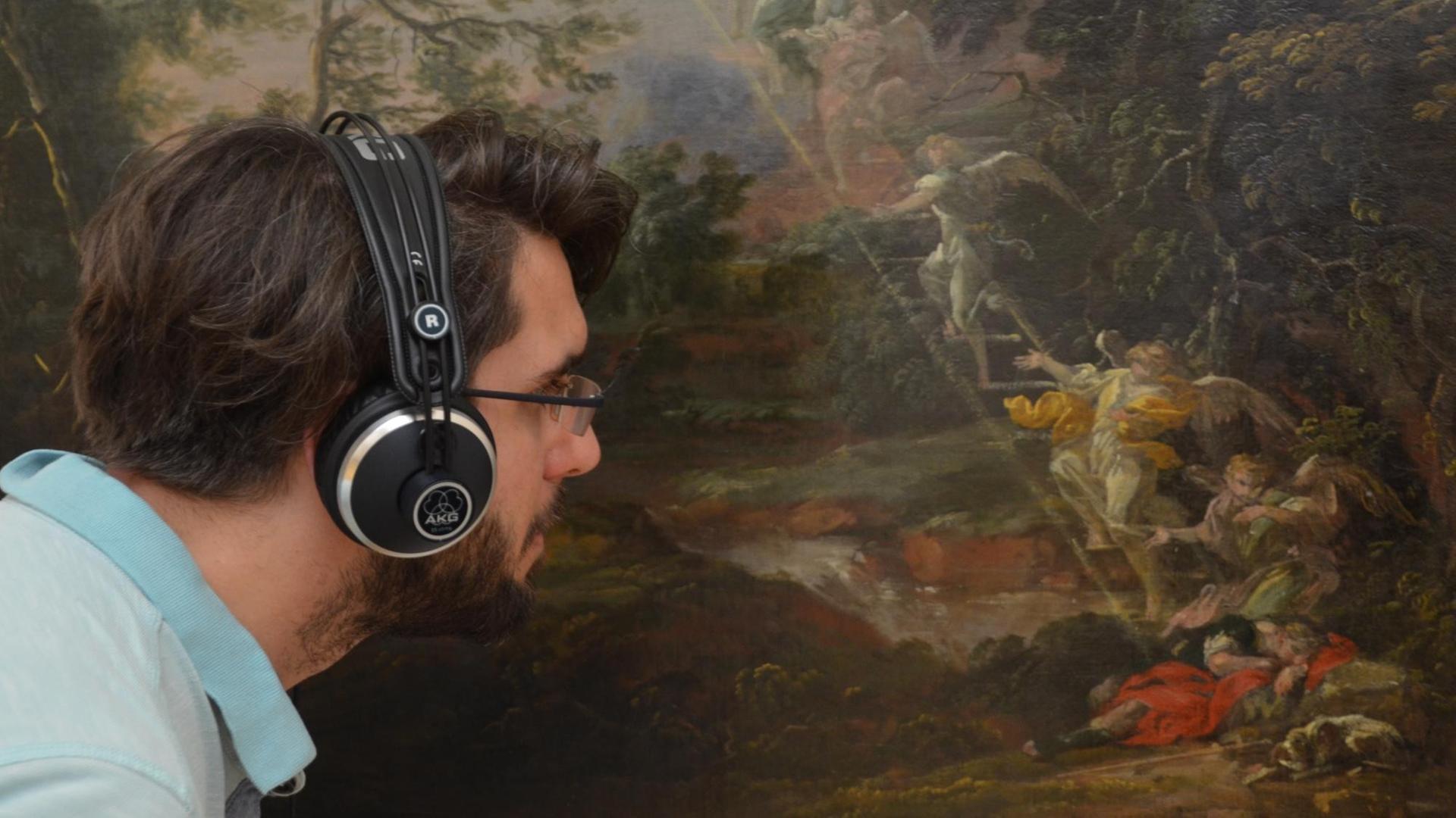 Ein Mann mit Kopfhörern betrachtet Michael Willmanns "Landschaft mit dem Traum Jakobs" (vermutlich 1691)