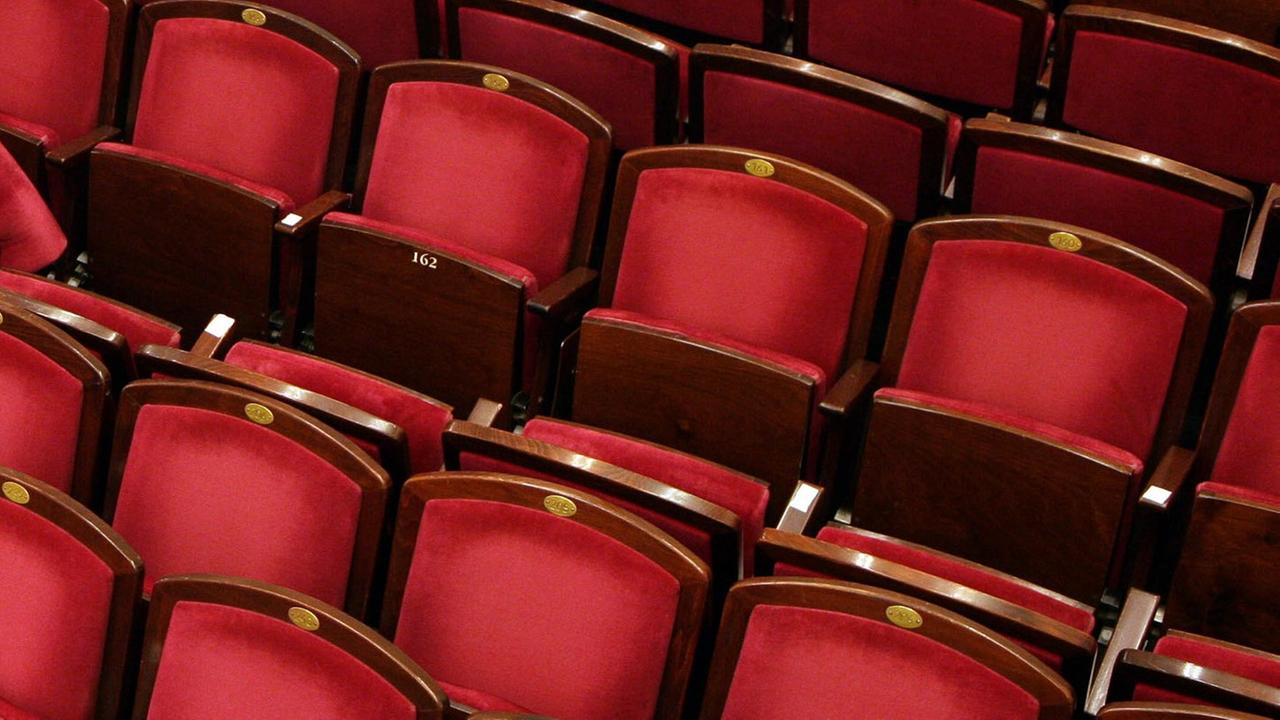 Rote Theaterstühle im Bühnenraum eines Theaters.