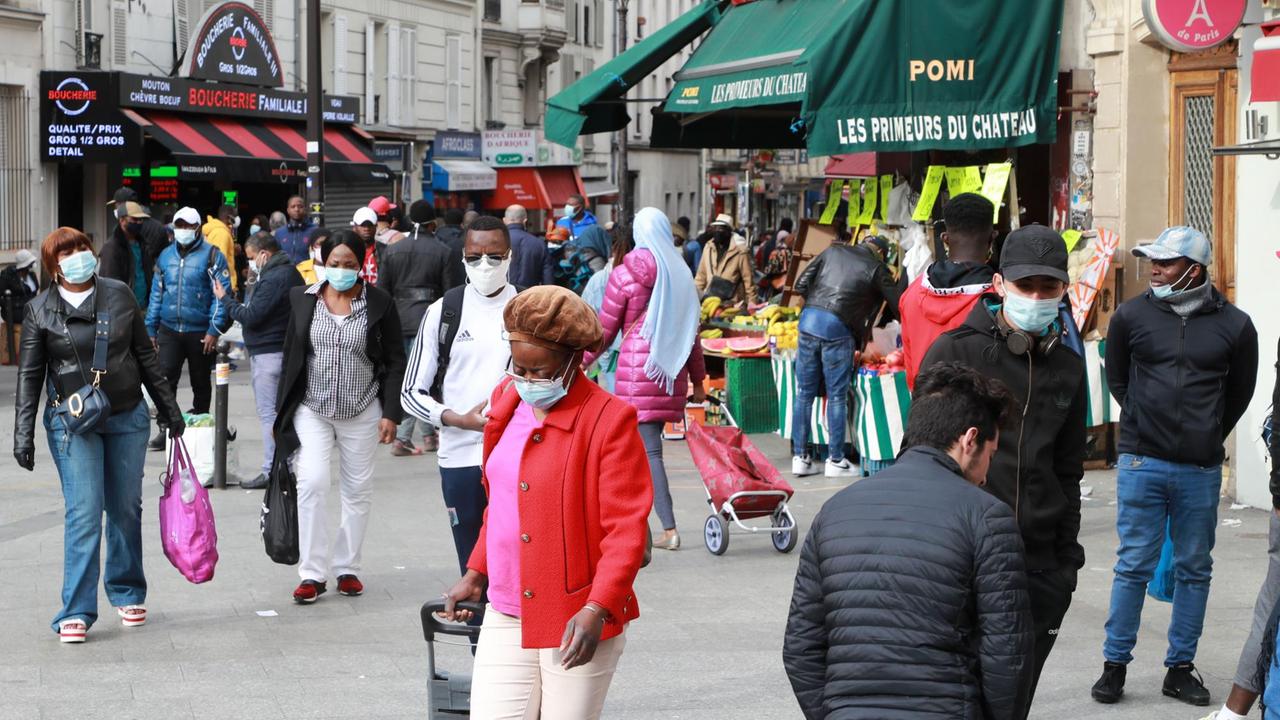 Menschen mit Mund-Nasen-Schutzmasken gehen am 12. Mai 2020 durch das Pariser Viertel Goutte d'Or