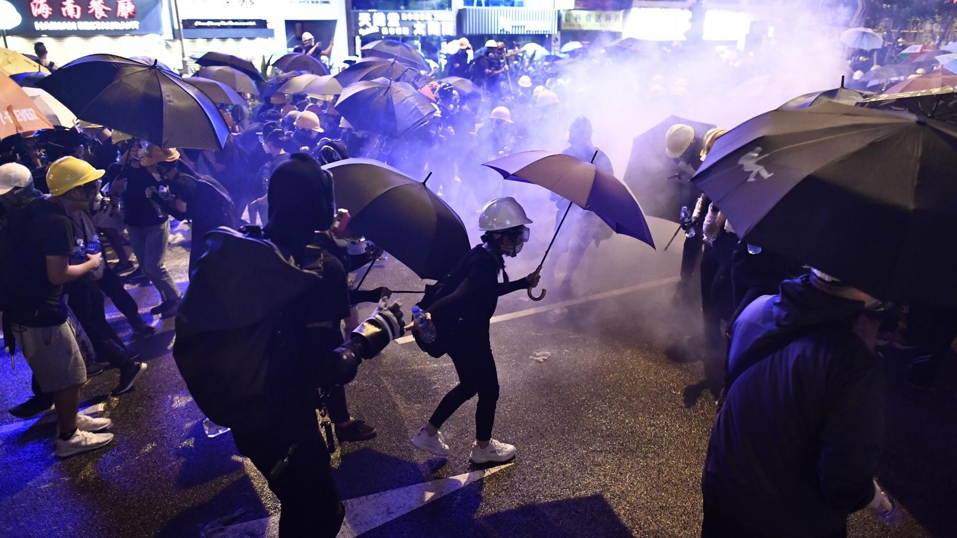 Eskalation in Hongkong: Mit Regenschirmen und Gasmasken versuchen sich die Demonstranten vor dem Tränengas der Polizei zu schützen.