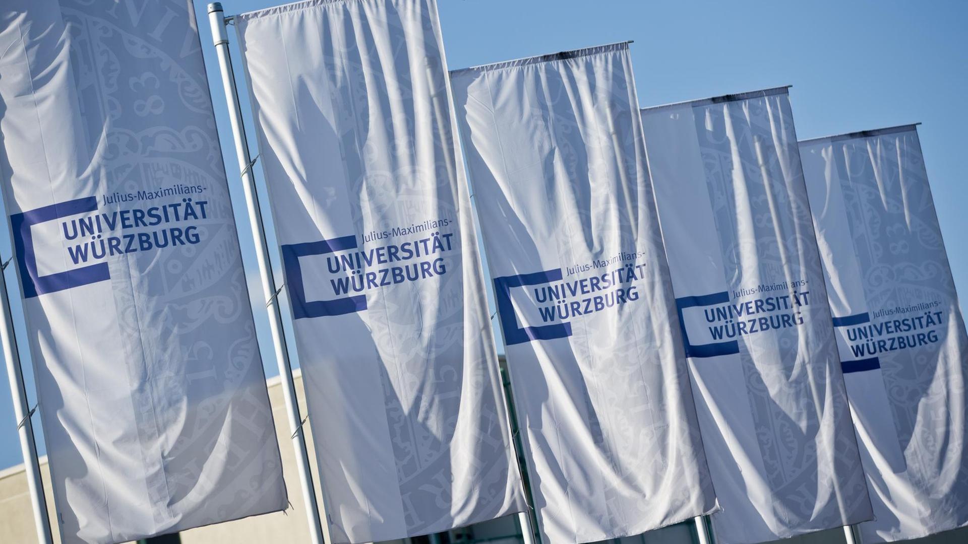 Flaggen mit dem Schriftzug "Universität Würzburg" wehen im Wind.