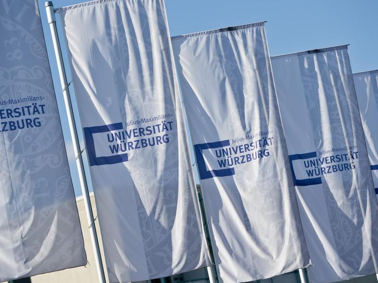 Flaggen mit dem Schriftzug "Universität Würzburg" wehen im Wind.