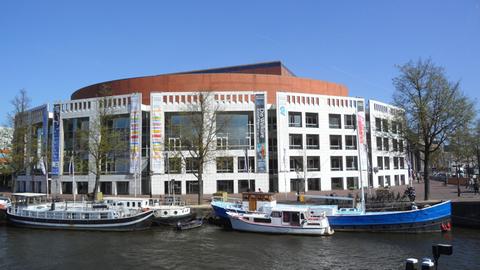 Blick über eine Gracht mit verschiedenen Booten auf die Oper in Amsterdam