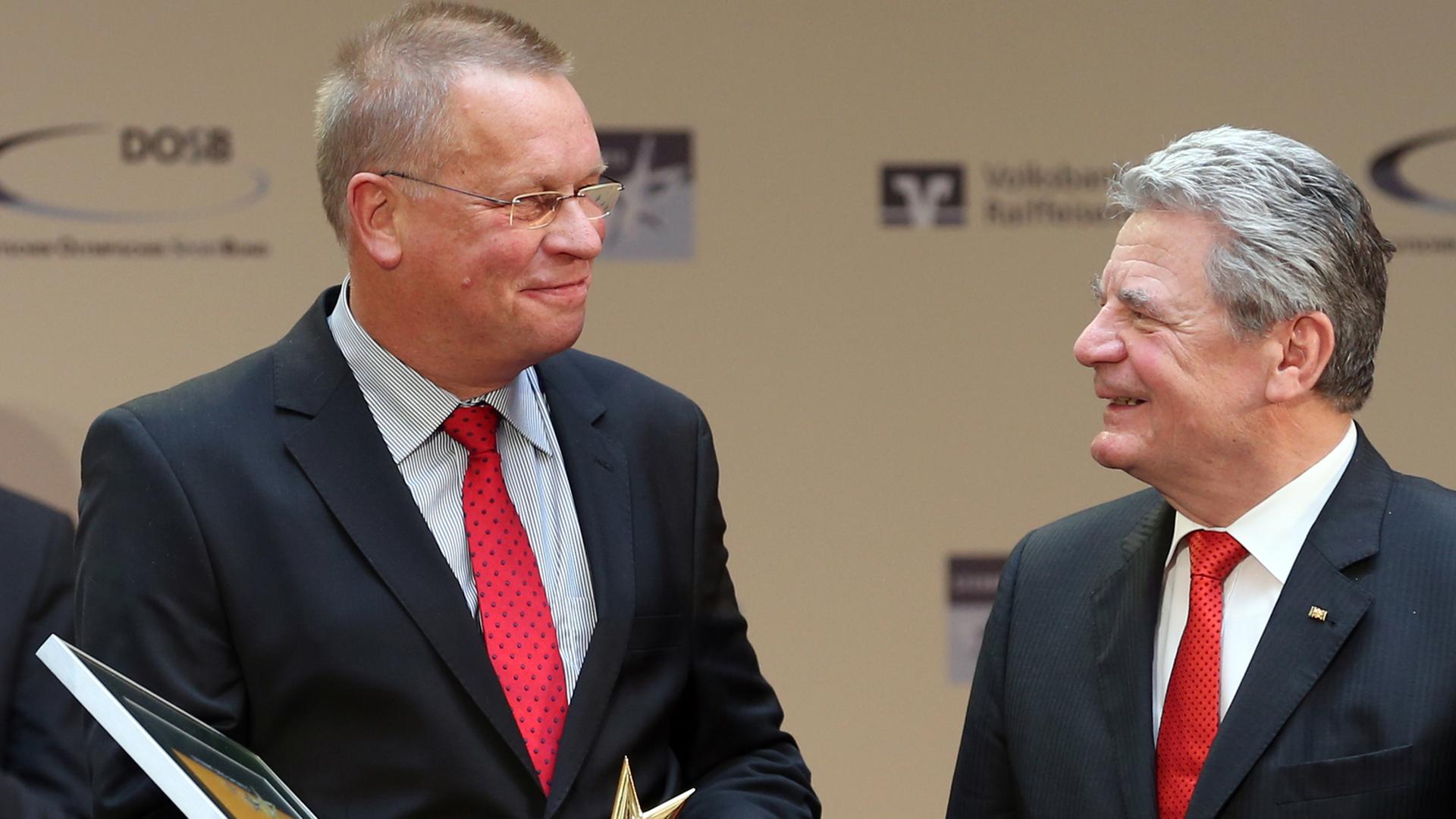 Rolf Jägersberg steht neben Bundespräsident Joachim Gauck und hält eine gerahmte Urkunde und den "Großen Stern des Sports" in Gold in den Händen.