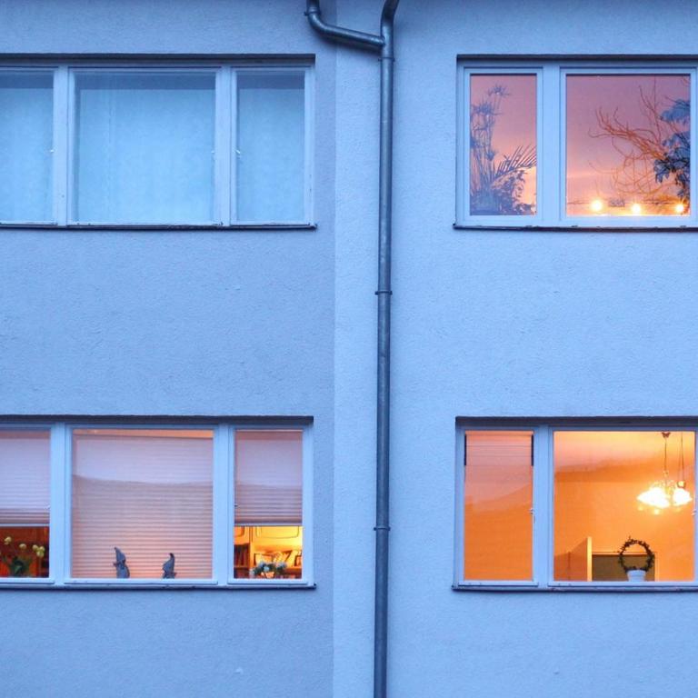 Berlin. In einem Mehrfamilienhaus im Bezirk Steglitz-Zehlendorf sind in der Abenddämmerung bereits einige Fenster erleuchtet. 