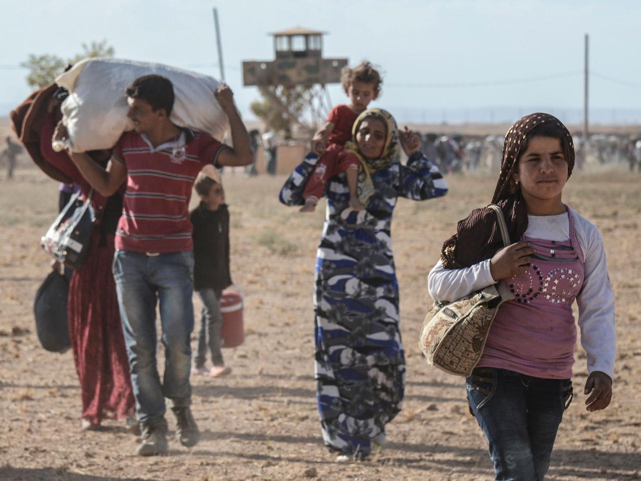 Syrische Kurden überqueren die Grenze zur Türkei.