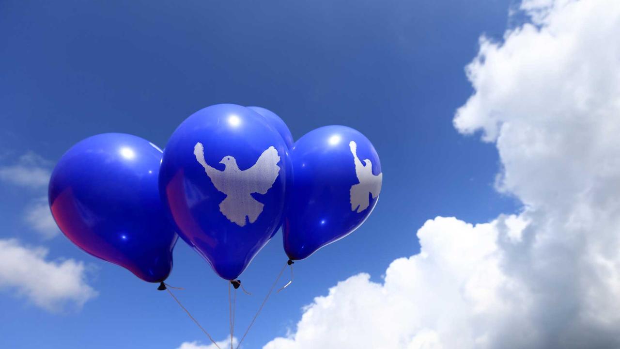 Blaue Luftballons mit dem Symbol einer Friedenstaube schweben am 23.08.2014 in Letzlingen (Sachsen-Anhalt) in der Luft