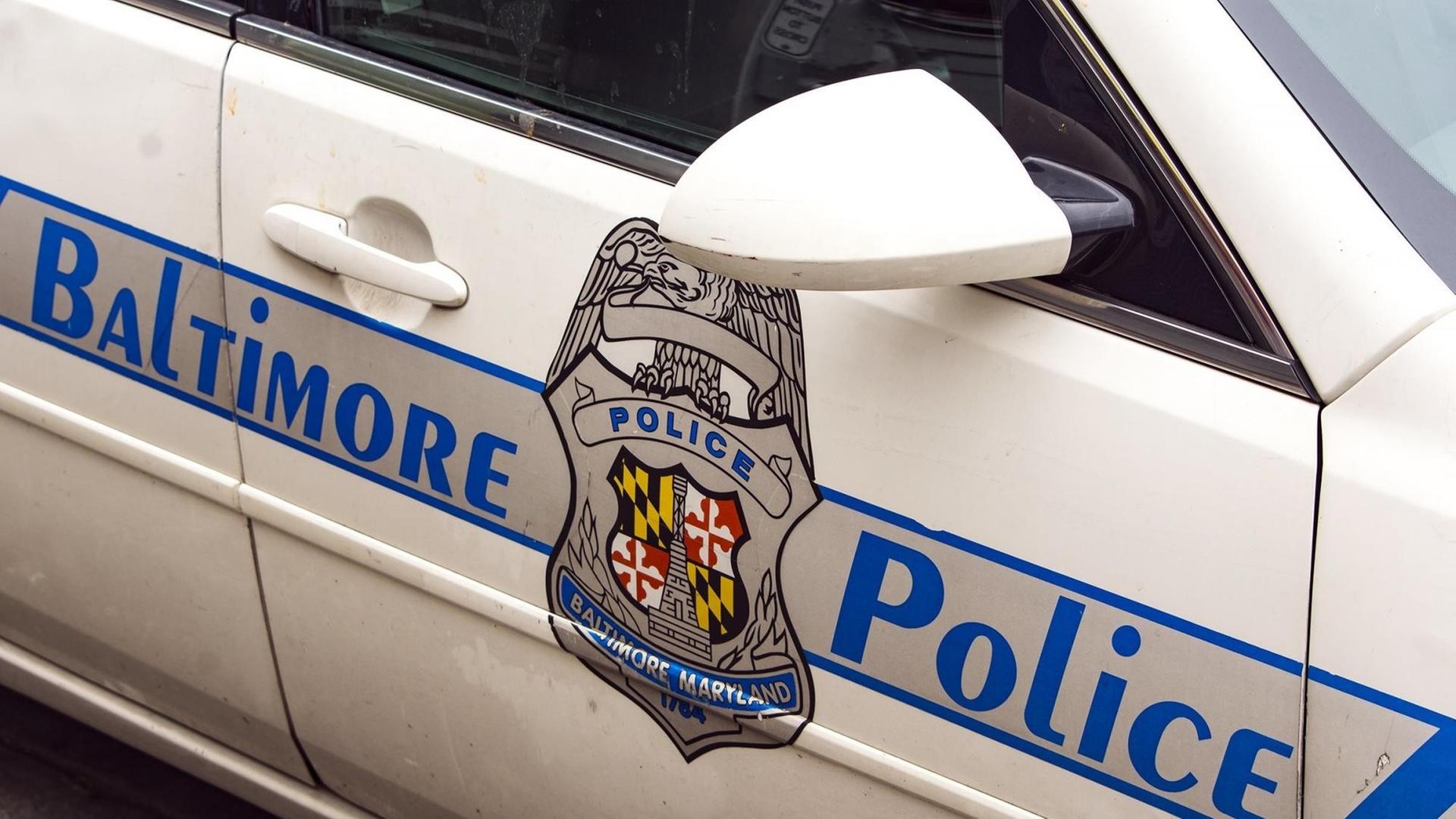 Das Bild zeigt die Tür eines weißen Polizei-Fahrzeugs. Auf dem Aufdruck steht "Baltimore Police", in der Mitte sieht man das Polizeiwappen. Das Bild zeigt die Tür eines weißen Polizei-Fahrzeugs. Auf dem Aufdruck steht "Baltimore Police", in der Mitte sieht man das Polizeiwappen.