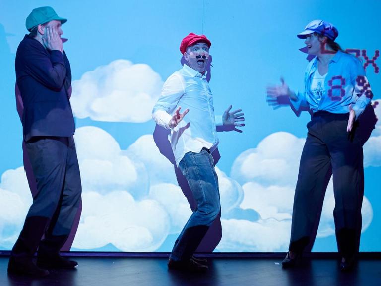 Die Schauspieler Ilja Harjes, Thomas Mehlhorn und Rose Lohmann stehen vor einem Plakat mit Wolken auf einer Bühne