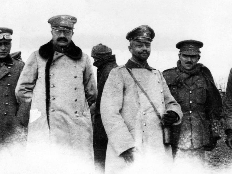 Schwarz-weiß-Foto deutscher und britischer Offiziere im Niemandsland während des inoffiziellen Waffenstillstands an Weihnachten 1914 im Ersten Weltkrieg. Sie stehen nebeneinander und schauen in die Kamera.