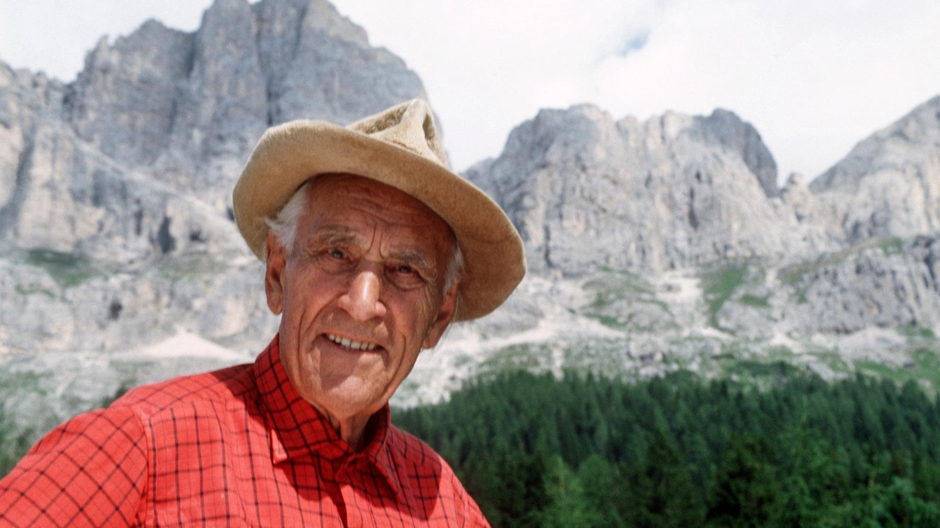 Ein Portrait von Luis Trenker mit den südtiroler Bergen im Hintergrund.
