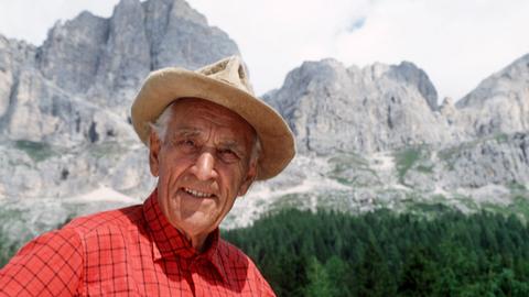 Ein Portrait von Luis Trenker mit den südtiroler Bergen im Hintergrund.