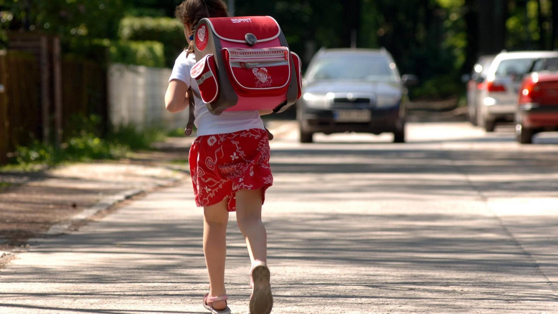 Ein Mädchen mit einem Schulranzen läuft über eine Straße