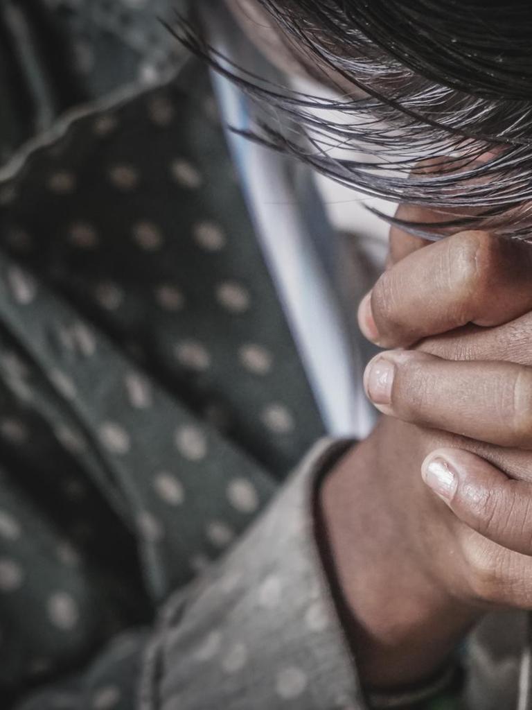 Hände, die um Verzeihung betend gefaltet sind, mit gesenktem Kopf.