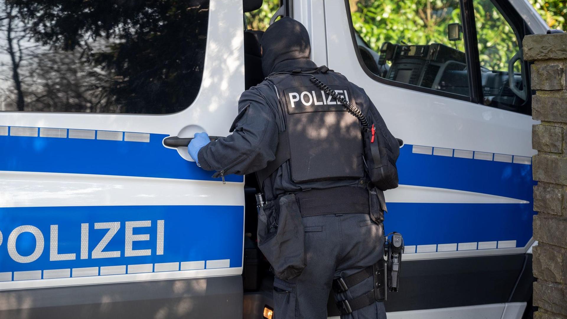 Ein Polizist steht im Rahmen einer Razzia an einem Polizeifahrzeug. Ein Polizist steht im Rahmen einer Razzia an einem Polizeifahrzeug.