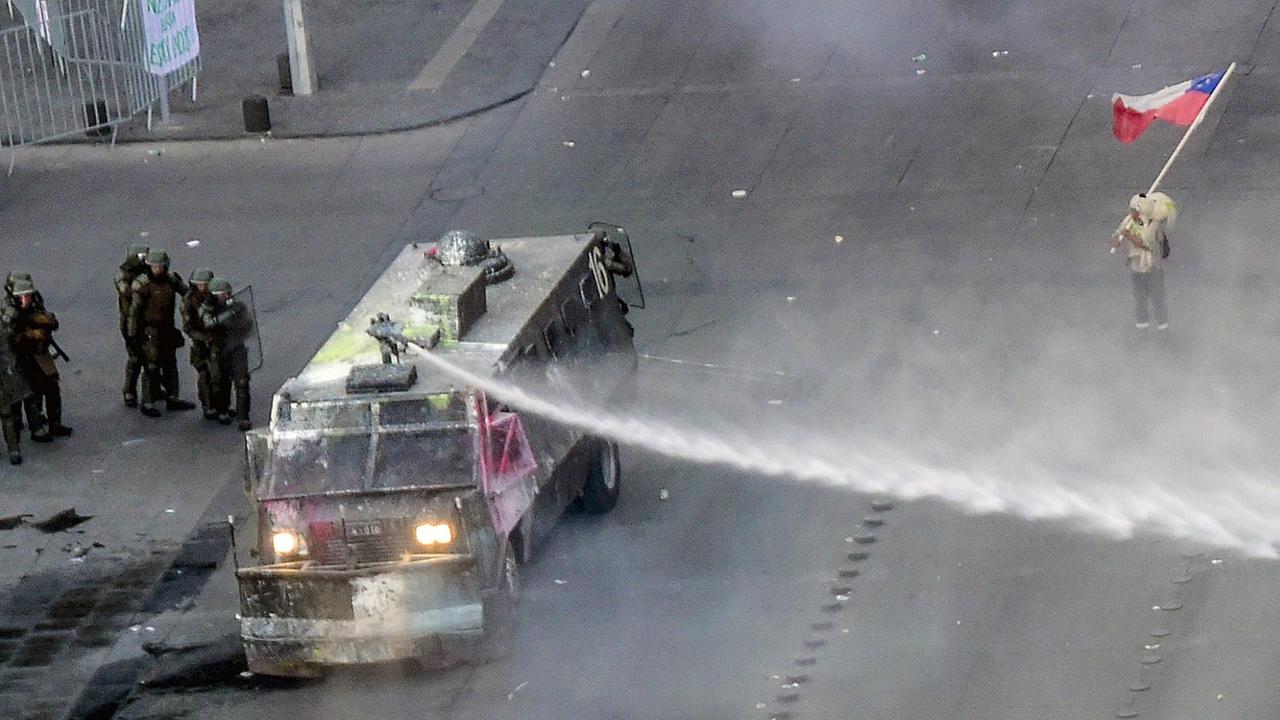 Ein einzelner Mann steht auf der Straße und demonstriert vor einem Fahrezug der Polizei.