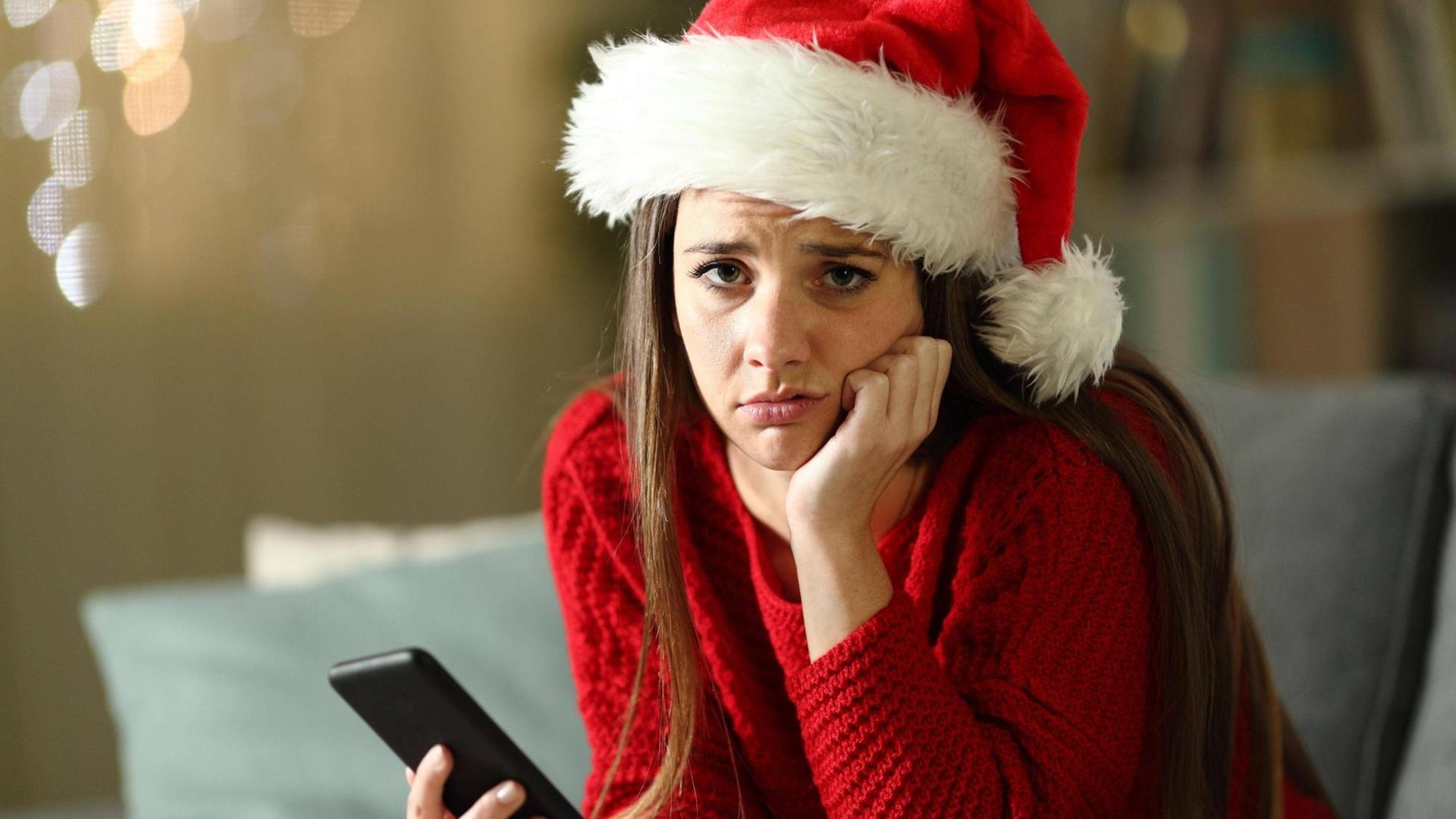 Eine traurig dreinblickende Frau in einem Weihnachtsoutfit.
