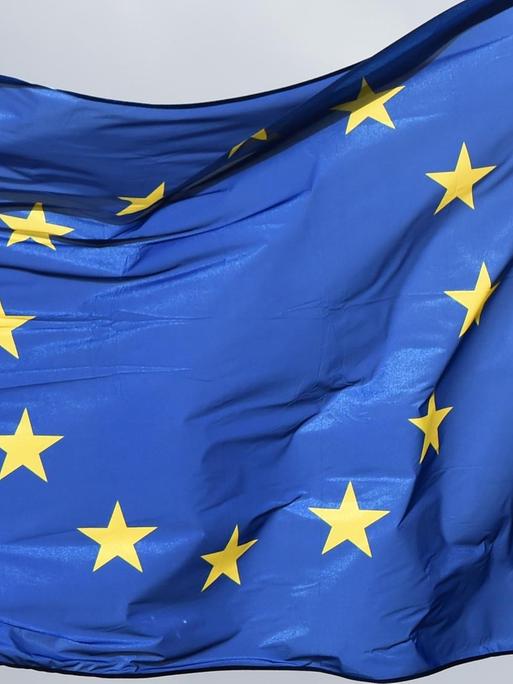 Die blaue Europaflagge mit 12 gelben Sternen im Kreis weht im Wind.