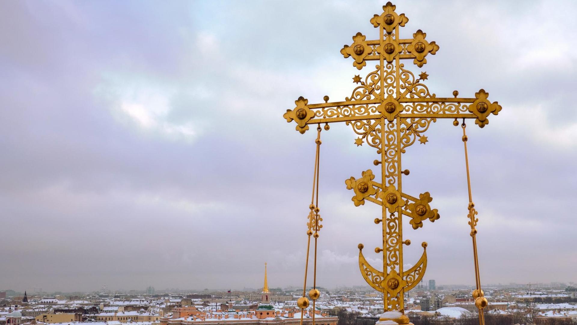 Das Kreuz der Auferstehungskirche in St. Petersburg ist vor dem Panorama der Stadt zu sehen.