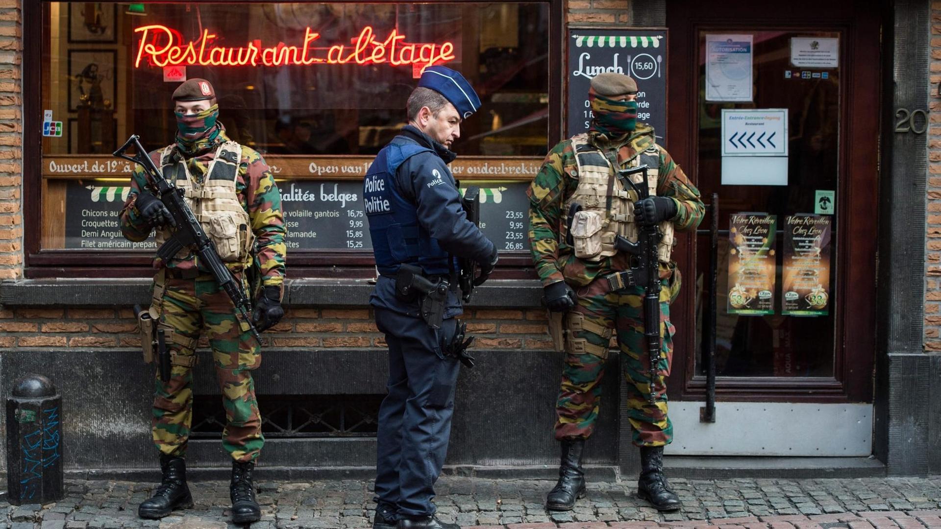 Ein Polizist und zwei Soldaten sichern ein Restaurant in der belgischen Hauptstadt Brüssel.