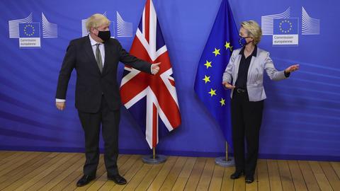 Boris Johnson und Ursula von der Leyen in Brüssel. Sie stehen vor Fahnen der Europäischen Union und Großbritanniens. Beide tragen Masken. Sie sehen sich an, von der Leyen macht eine einladende Geste.