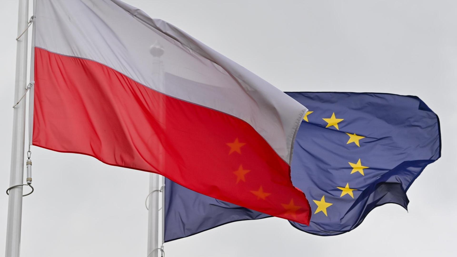 Die weiß-rote Nationalfahne Polens und dahinter die Fahne der Europäischen Union (EU) wehen im Wind