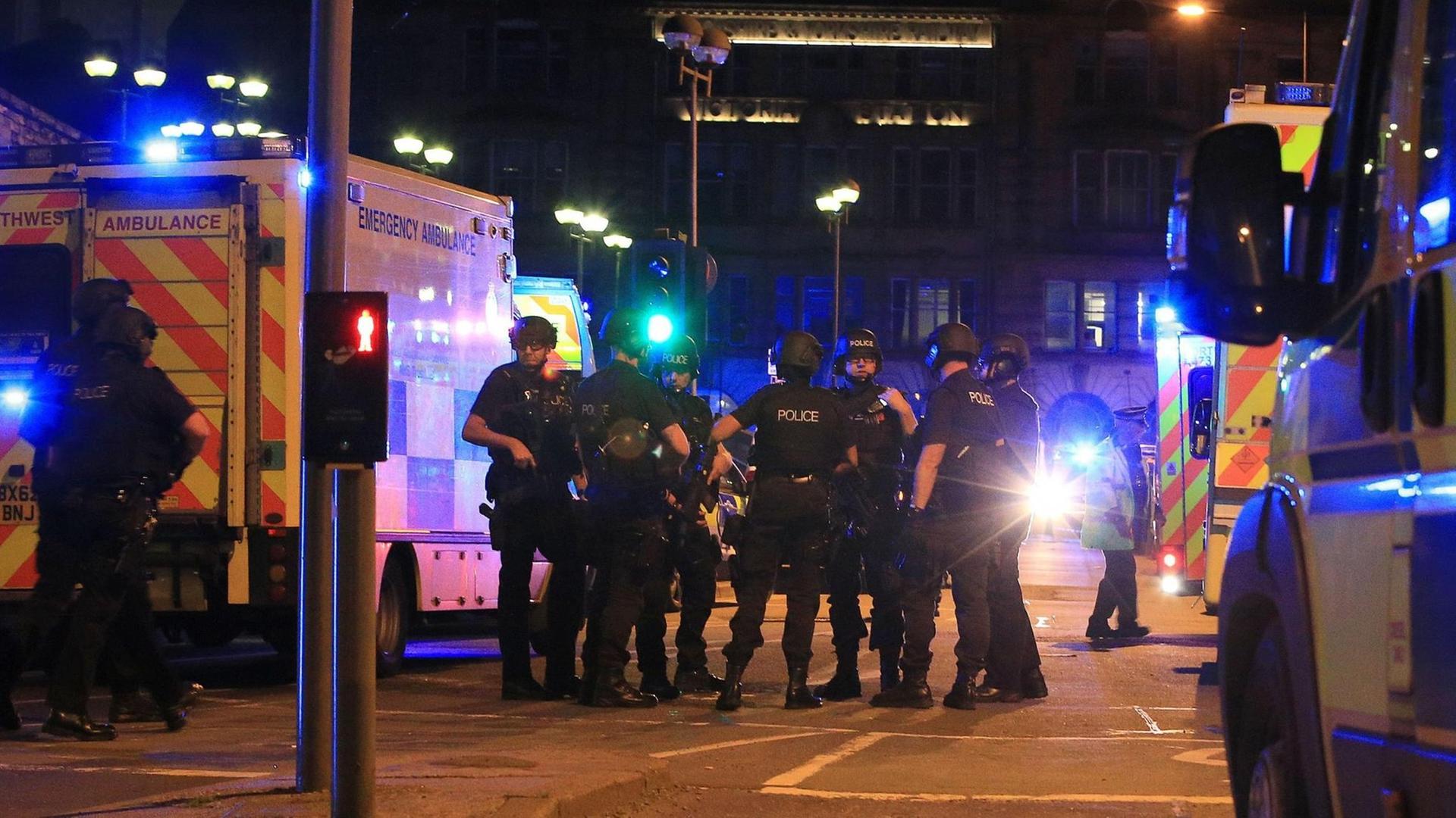 Bewaffnete Polizisten und Einsatzfahrzeuge mit Blaulicht an der Arena in Manchester.