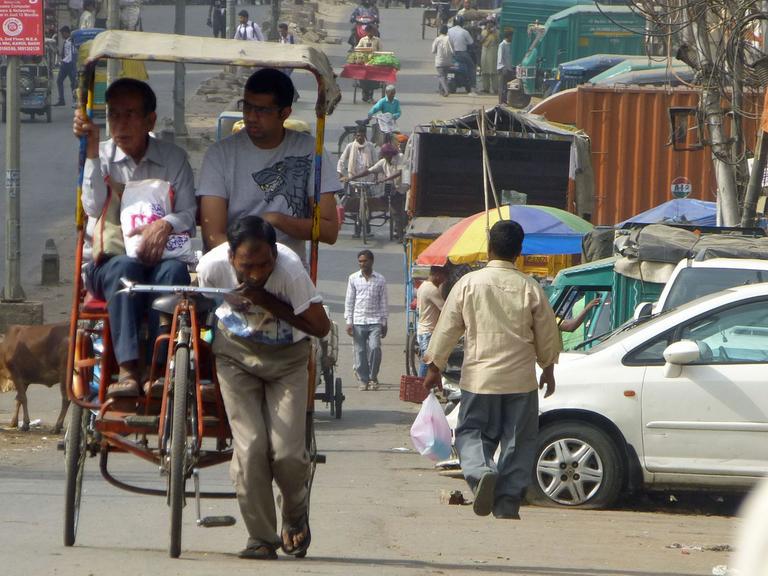 Alltag in Old Delhi: Ein Mann zieht eine Rikscha samt Passagieren.