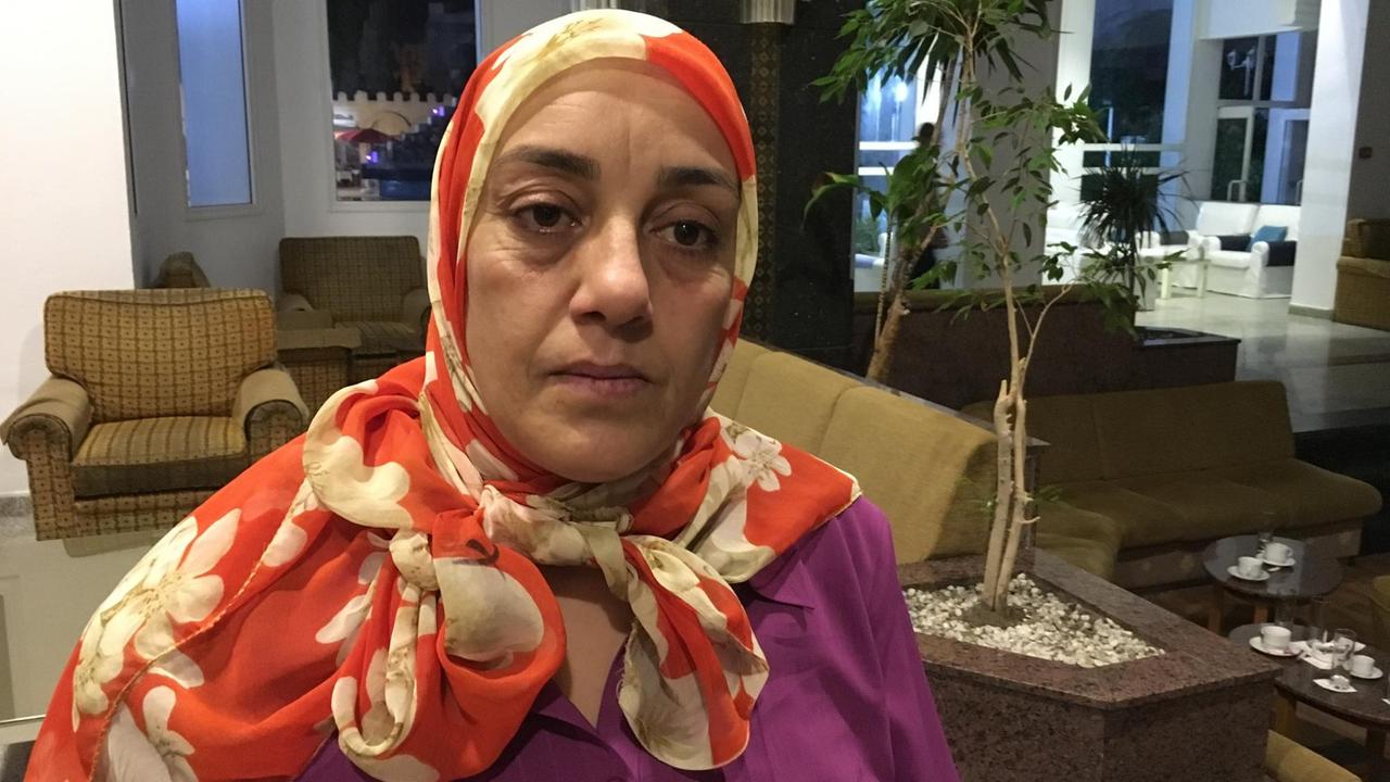 Die Tunesierin Basma Chaker in einer violetten Bluse in einem größeren Büroraum.
