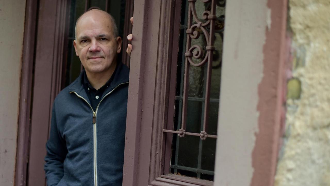 Der Schriftsteller Frank Witzel steht lässig in einem Hauseingang und blickt auf die Straße