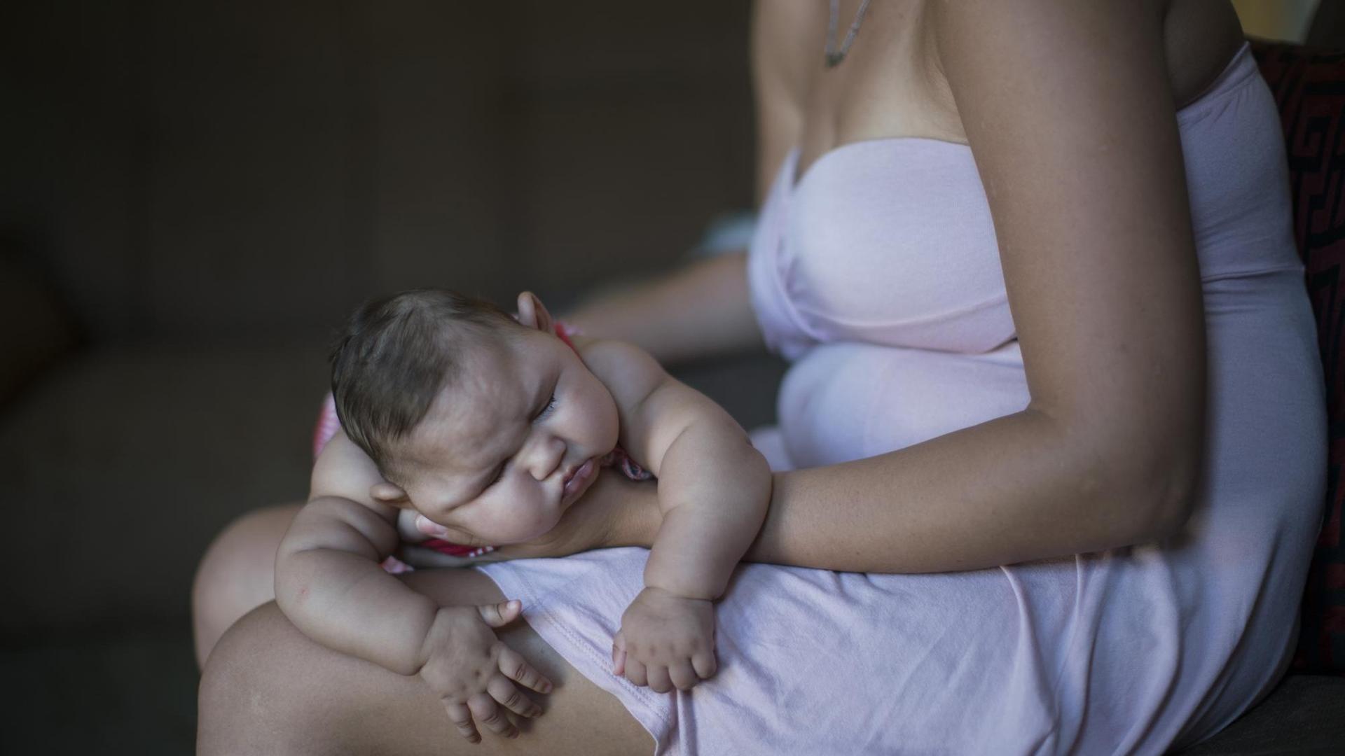 Eine Frau in Brasilien hält ihr Baby, das einen zu kleinen Kopf hat. 