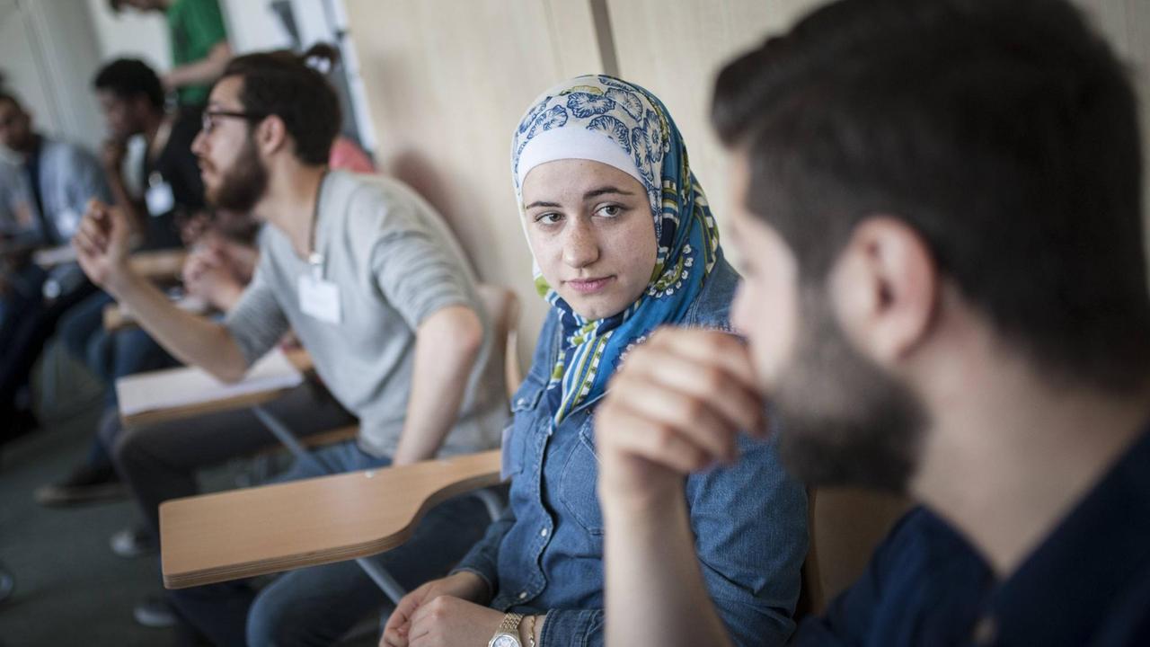 Flüchtlinge - eine junge Frau und mehrere Männer - nehmen an einem Vorbereitungs-Kurs an der Freien Universität in Berlin teil.