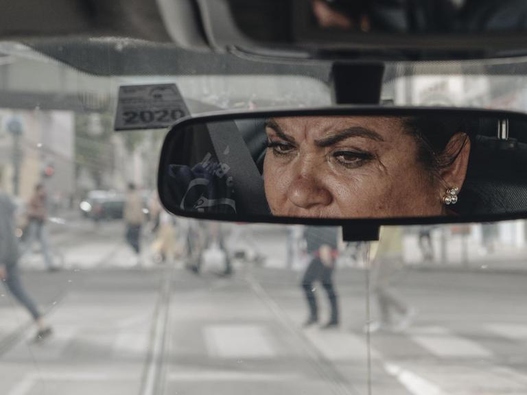 Das Gesicht einer Frau ist im Rückspiegel ihres Autos zu sehen.