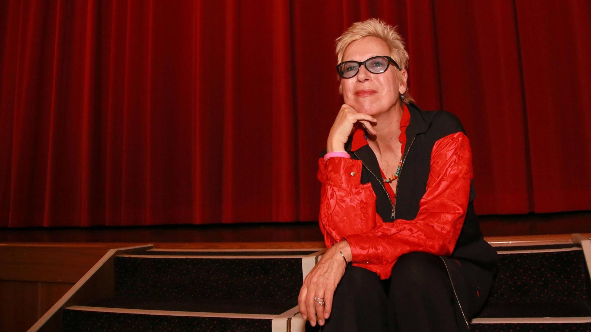 Die Regisseurin Doris Dörrie sitzt vor einem roten Vorhang in einem Kinosaal in Essen.