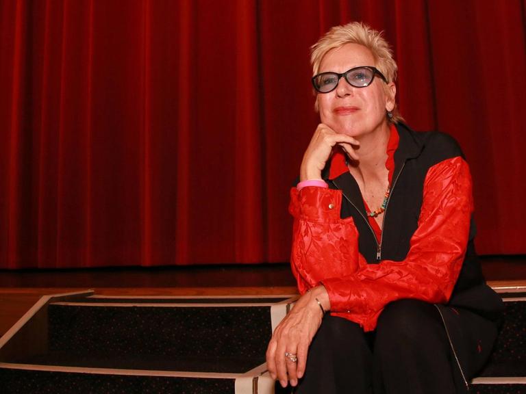 Die Regisseurin Doris Dörrie sitzt vor einem roten Vorhang in einem Kinosaal in Essen.