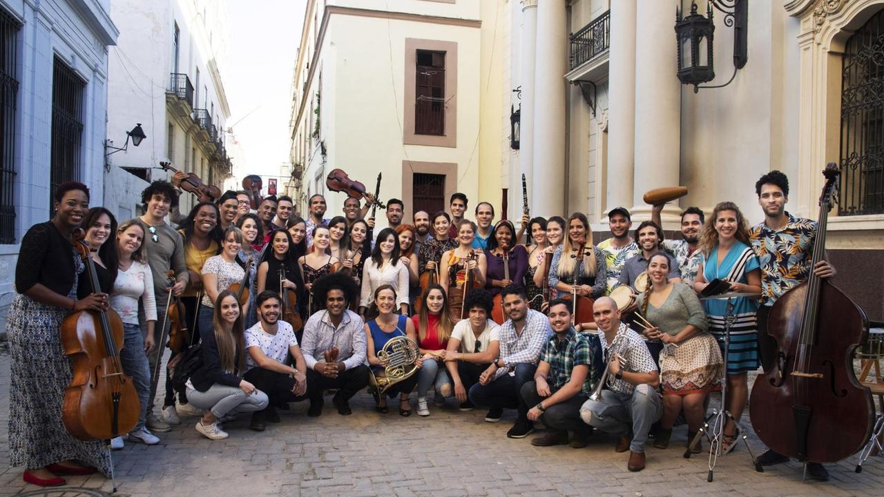 Das Orchester und die Hornistin Sarah Willis posieren gemeinsam mit ihren Instrumenten in einer Straße in Havanna.