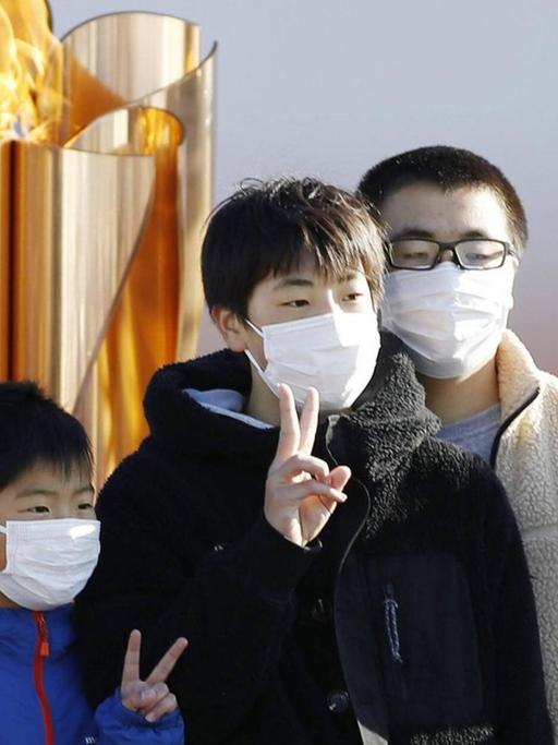 Junge Japaner posieren mit dem Victory-Zeichen vor der Olympischen Flamme im Nordosten des Landes.