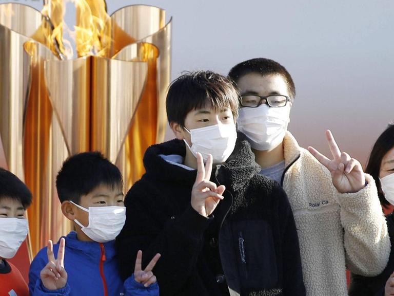 Junge Japaner posieren mit dem Victory-Zeichen vor der Olympischen Flamme im Nordosten des Landes.