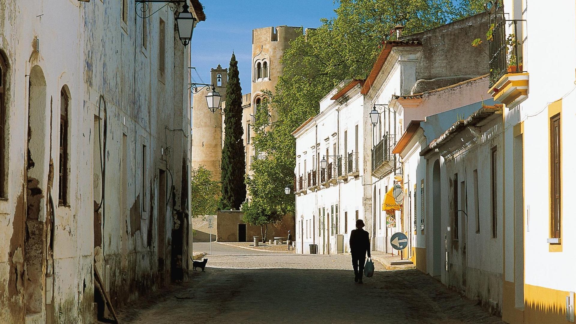 Eine Gasse im Dorf Alvito in Portugal, im Hintergrund ist das Kastell zu sehen