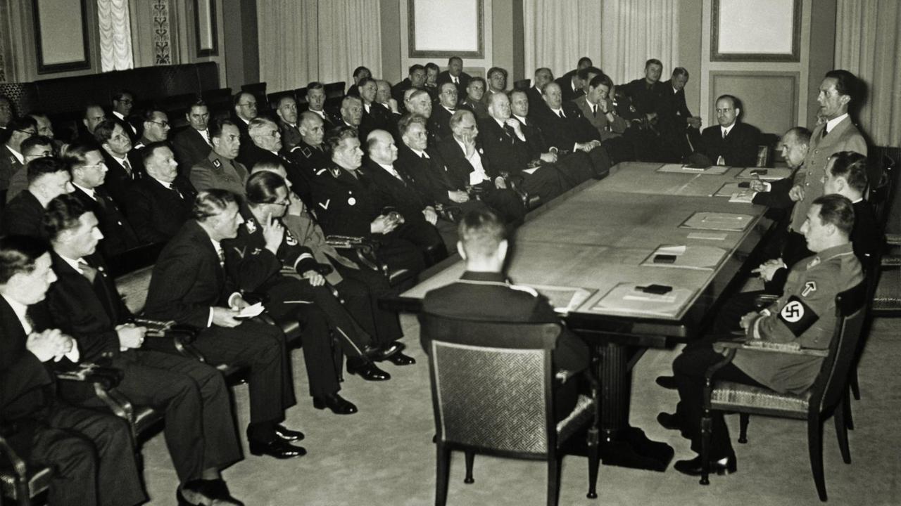 Das historische Foto von 1936 zeigt Joseph Goebbels als Präsident der Reichskulturkammer während seiner Ansprache; rechts von ihm sind Staatsekretär Funk und Ministerialrat Hanke zu sehen, links Reichskulturverwalter. Hinkel.