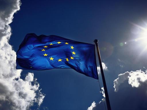 Die Fahne der Europäischen Union weht im Wind und wird von der Sonne angestrahlt. Gewitterwolken ziehen vorbei. Die Fahne der Europäischen Union weht im Wind und wird von der Sonne angestrahlt. Gewitterwolken ziehen vorbei.