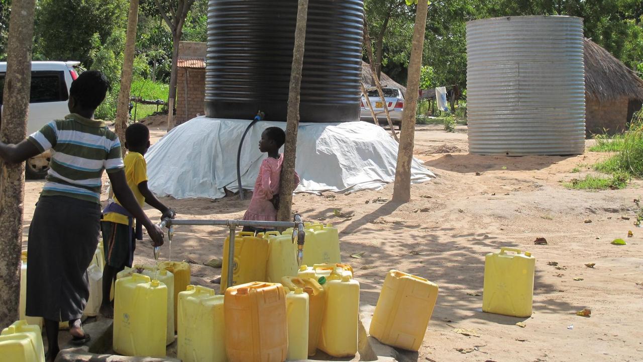 Südsudanesen warten auf den Wassertruck im Rhinocamp. Gelbe Wasserkanisten sind leer.