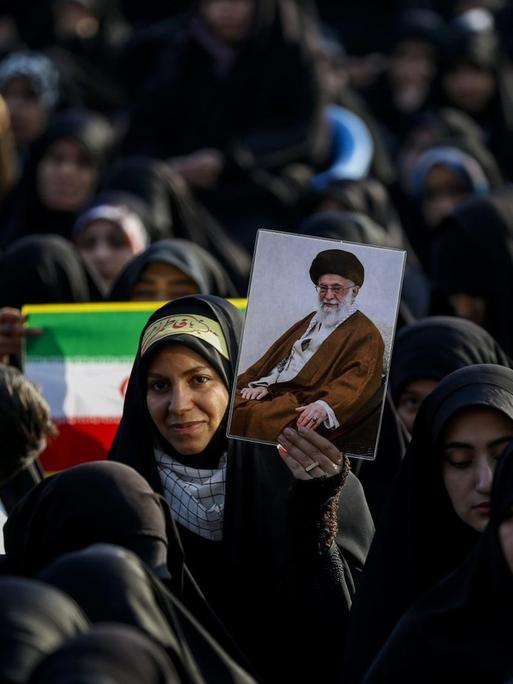 Frauen und Mädchen stehen am 31. Januar 2019 zusammen. Eine hält eine iranische Flagge hoch, eine andere das Bild von Revolutionsführer Ayatollah Khomeini