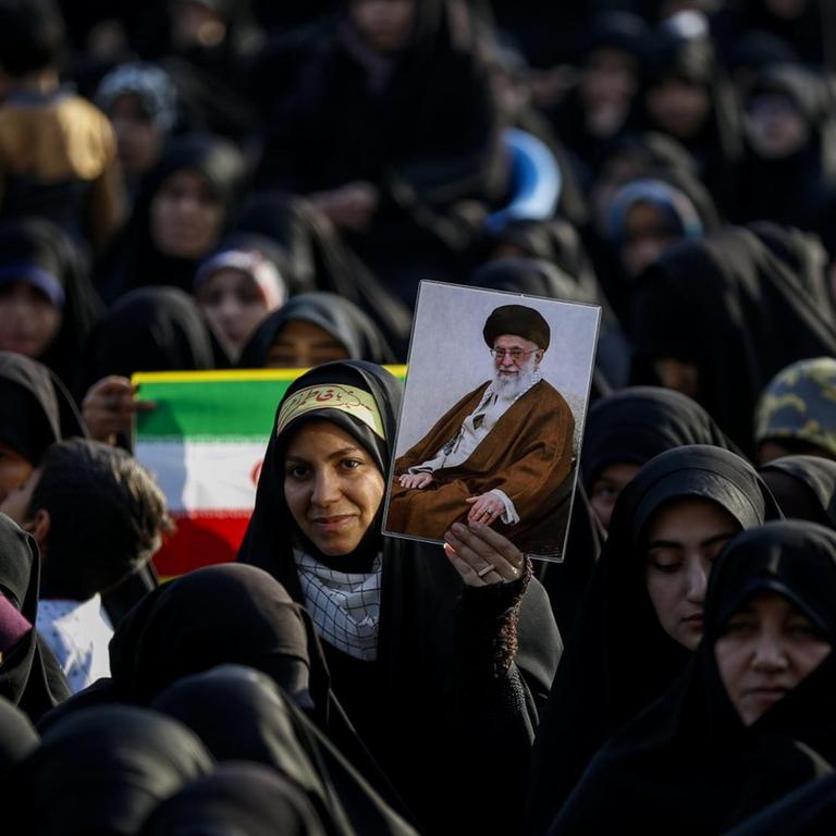 Frauen und Mädchen stehen am 31. Januar 2019 zusammen. Eine hält eine iranische Flagge hoch, eine andere das Bild von Revolutionsführer Ayatollah Khomeini