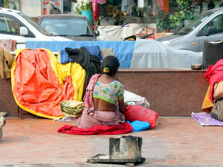 Eine Frau sitzt Old-Delhi in Indien am Straßenrand neben ihrer provisorischen Unterkunft, aufgenommen 2014.