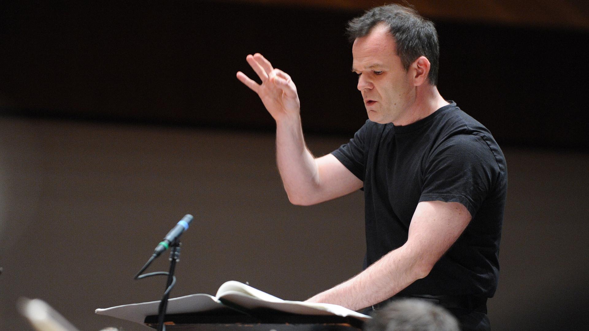 Francois-Xavier Roth hebt die rechte Hand und dirigiert ein nicht sichtbares Orchester